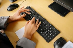 Close-up of hands typing on keyboard in finance office environment