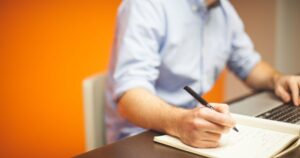 Person writing a cover letter on a laptop at a desk